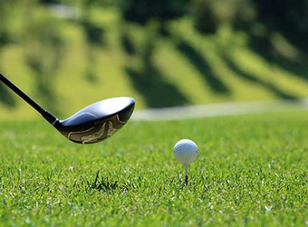 Golfschläger und Golfball auf einem Abschlagplatz im Grünen